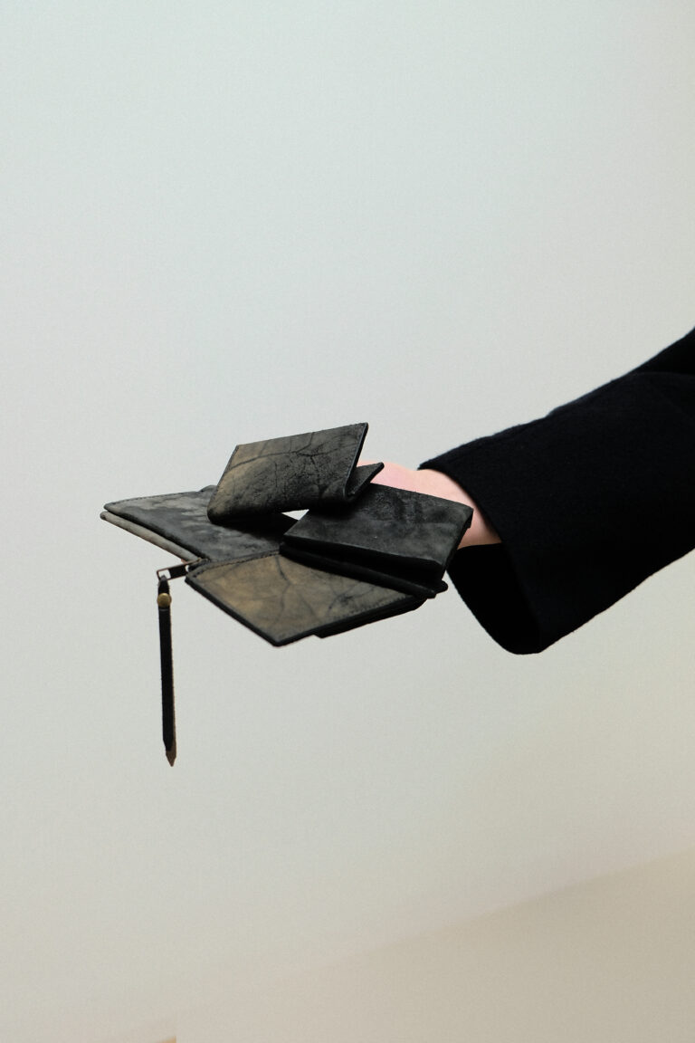 Ein Model hält das wallet charta, coinpocket aspratura, wallet argentaria und den businesscardholder kept